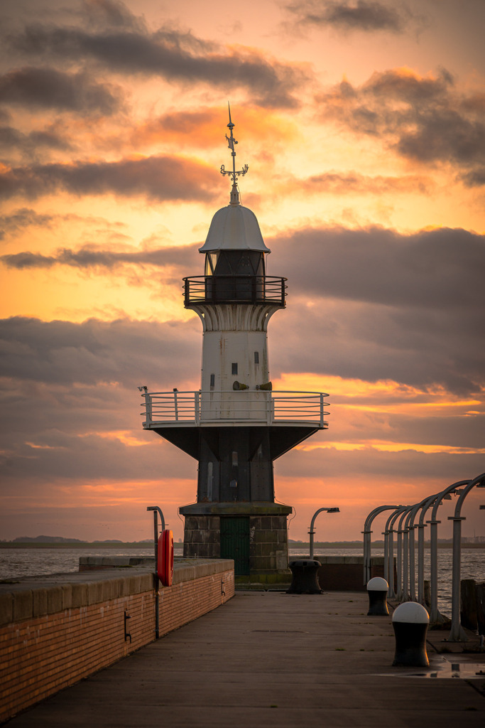 Leuchtturm "Mole 1" Brunsbüttel | Der historische Leuchtturm "Mole 1" in Brunsbüttel präsentiert sich majestätisch vor dem beeindruckenden Hintergrund eines malerischen Sonnenuntergangs. In diesem idyllischen Szenario wird der Leuchtturm "Mole 1" zu einem zeitlosen Symbol der Schifffahrtsgeschichte, das in der malerischen Kulisse eines Sonnenuntergangs seinen ganz eigenen Charme entfaltet.