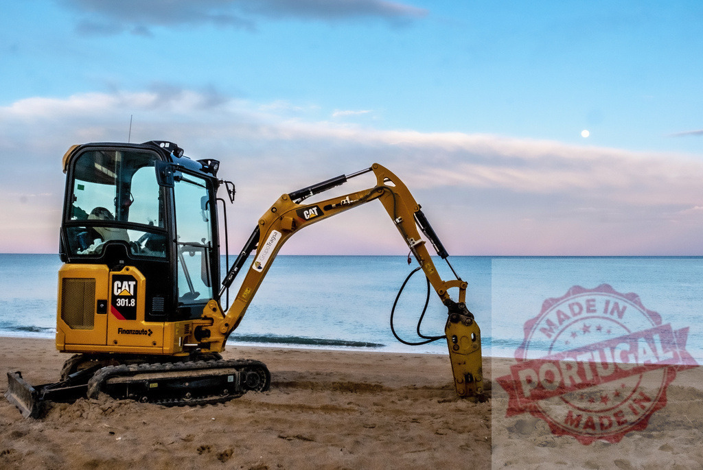 CAT mini excavator working on beach at sunset | CAT mini excavator resting on sandy beach with ocean and sky at sunset - Realisiert mit Pictrs.com