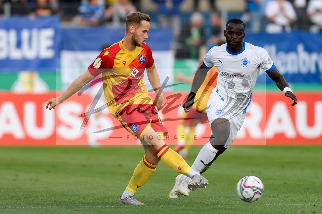 LOTKSC20210809_155 | Fussball, Herren: Christoph Kobald (Karlsruher SC) und Exauce Andzouana (Sportfreunde Lotte) im Zweikampf beim Spiel der 1. Runde im DFB-Pokal zwischen SF Lotte und Karlsruher SC im Stadion am Lotter Kreuz am 09.08.2021 in Lotte, Deutschland.DFB / DFL REGULATIONS PROHIBIT ANY USE OF PHOTOGRAPHS AS IMAGE SEQUENCES AND/OR QUASI-VIDEO. - Realisiert mit Pictrs.com