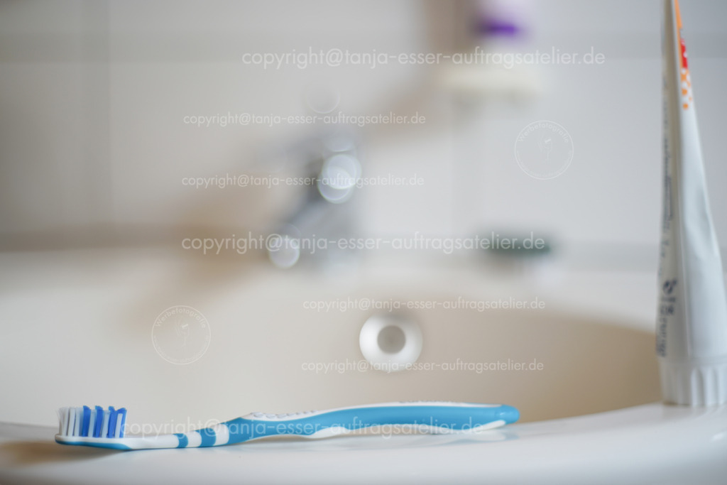 Tooth brush at bathroom 2 D | Blaue Zahnbürste liegt auf einem Spülbecken im Badezimmer. Unscharfer Hintergrund mit Copy Space und Bokeh.