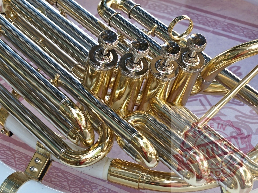 Shiny brass sousaphone valves and tubing reflecting light | Close-up view of sousaphone valves and tubing, highlighting the instrument's polished brass finish and intricate details - Realisiert mit Pictrs.com