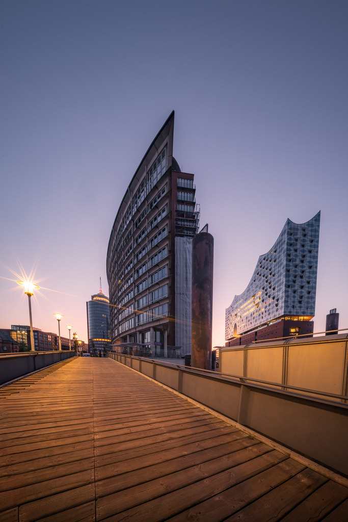 Elbphilharmonie und moderne Architektur in der HafenCity | Blick über die Promenade der Hamburger HafenCity auf die Elbphilharmonie und die umliegende moderne Architektur im warmen Abendlicht. - Realisiert mit Pictrs.com