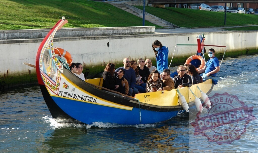 Moliceiro boat carrying tourists on Aveiro canal | People enjoying a traditional Moliceiro boat tour in Aveiro, Portugal - Realized with Pictrs.com