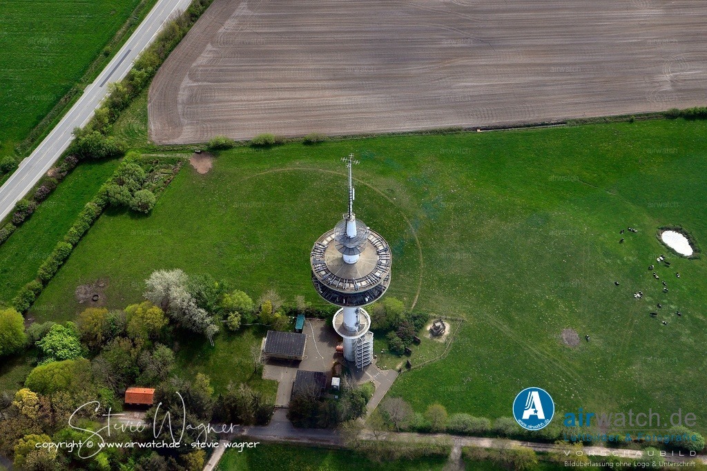 Luftbild - Der Stollberg bei Bredstedt in Nordfriesland | Der Fernmeldeturm Bredstedt wurde von 1975 bis 1976 erbaut und seitdem betrieben.  Der Bau erfolgte durch die Deutsche Bundespost, und der Turm ging 1976 in Betrieb. - 1. Bauzeit (1975–1976): Der Turm wurde von der Deutschen Bundespost errichtet und 1976 in Betrieb genommen. - 2. Umbau 2009: Am 28. Oktober 2009 wurde der Turm für die Ausspielung von digitalem Fernsehen (DVB-T) umgerüstet und übernimmt seitdem diese Funktion für weite Teile Nordfrieslands. - 3. Militärische Nutzung in der Nähe: Obwohl der Turm selbst zivil genutzt wurde, befand sich in der Nähe des Stollbergs eine unterirdische Horchstation des Bundesgrenzschutzes (BGS) im Bredstedter Koog, die bis kurz nach der Wende aktiv war.  Diese wurde später von der Stadt Bredstedt gekauft und für Fledermäuse als Schlafstätte umgewidmet. - 4. Öffentliche Aussichtsplattform: Seit dem Bau ist der Turm mit einer Aussichtsplattform in 20 Metern Höhe für die Öffentlichkeit zugänglich und bietet einen weiten Blick über Nordfriesland, die Nordsee und die Inseln.