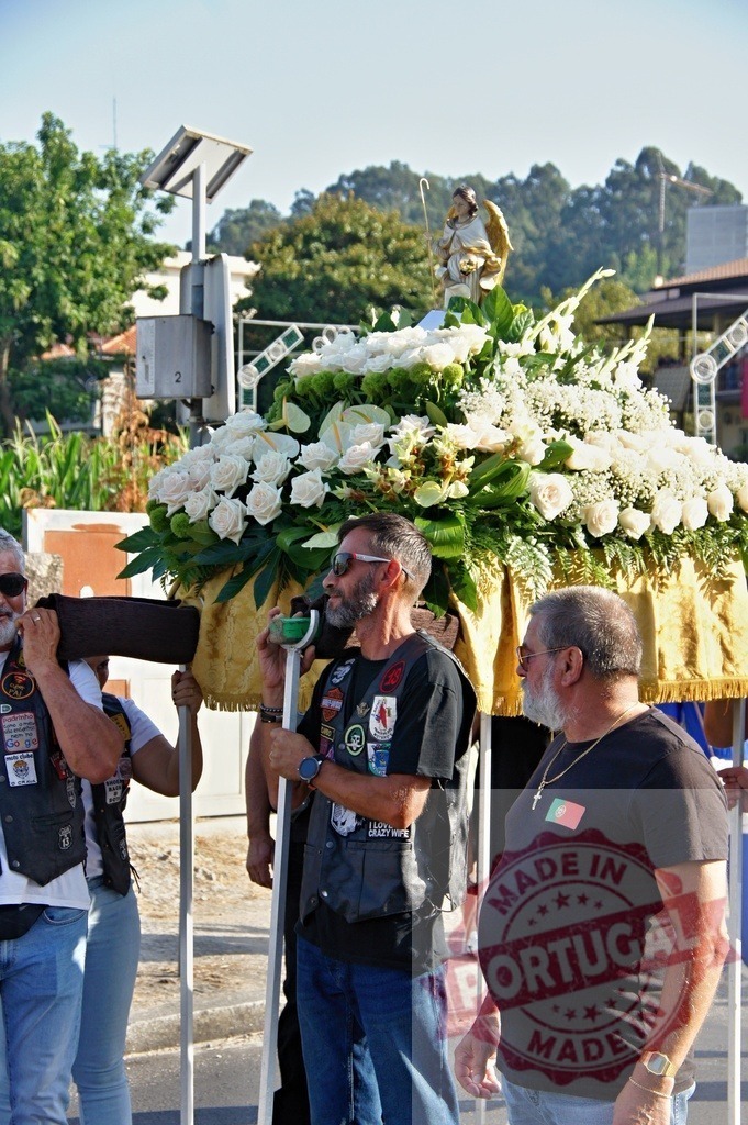 Bikers carrying religious float decorated with white flowers during a procession | Procession 15.08.2025 - Assumption Day - Paco de Sousa, Portugal Bikers carrying a religious float decorated with white flowers and topped by a statue of an angel during a procession - Realized with Pictrs.com