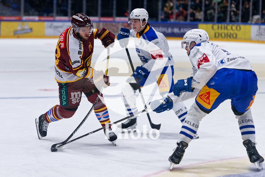National League - Geneve-Servette HC v EV Zug | Marc-Antoine Pouliot (78 Geneve-Servette HC) shoots the puck (action) under pressure of Colin Lindemann (95 EV Zug) Tobias Geisser (42 EV Zug)  during the National League match between Geneve-Servette HC and EV Zug at Les Vernets in Geneva, Switzerland