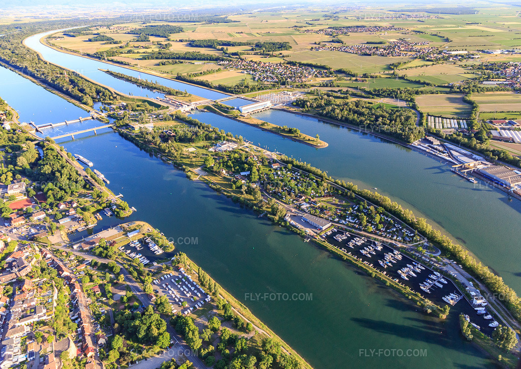 Aerial view: Rhine island with lock, Rhine bridge, marina in Vogelgrun in the state Haut-Rhin, France. – Photo: IMG_147845.jpg taken on 05/30/2025 by Werner Riehm/FLY-FOTO.com – Resolution of the original: 5151 x 3648 px