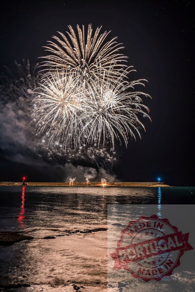Fireworks exploding over sea pier at night reflecting golden light | Fireworks bursting brightly above a pier and reflecting warm light on the ocean water - Realisiert mit Pictrs.com