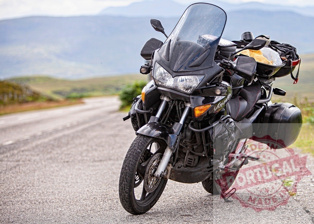 Black motorcycle parked on a winding mountain road | Black touring motorcycle standing on a remote paved road surrounded by mountains and distant hills - Realisiert mit Pictrs.com