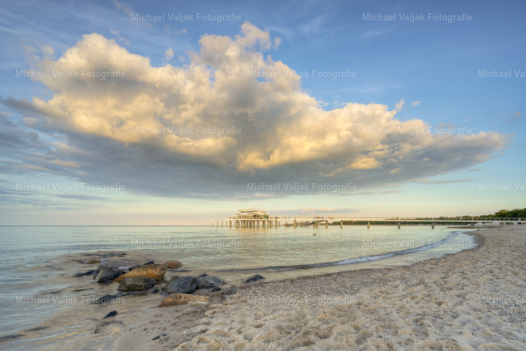 Am Timmendorfer Strand | Am Abend kurz vor Sonnenuntergang am Timmendorfer Strand. Eine große Wolke zieht über die Seebrücke in Richtung Ostsee und wird von der Sonne in ein gelbes Licht getaucht.  - Realisiert mit Pictrs.com
