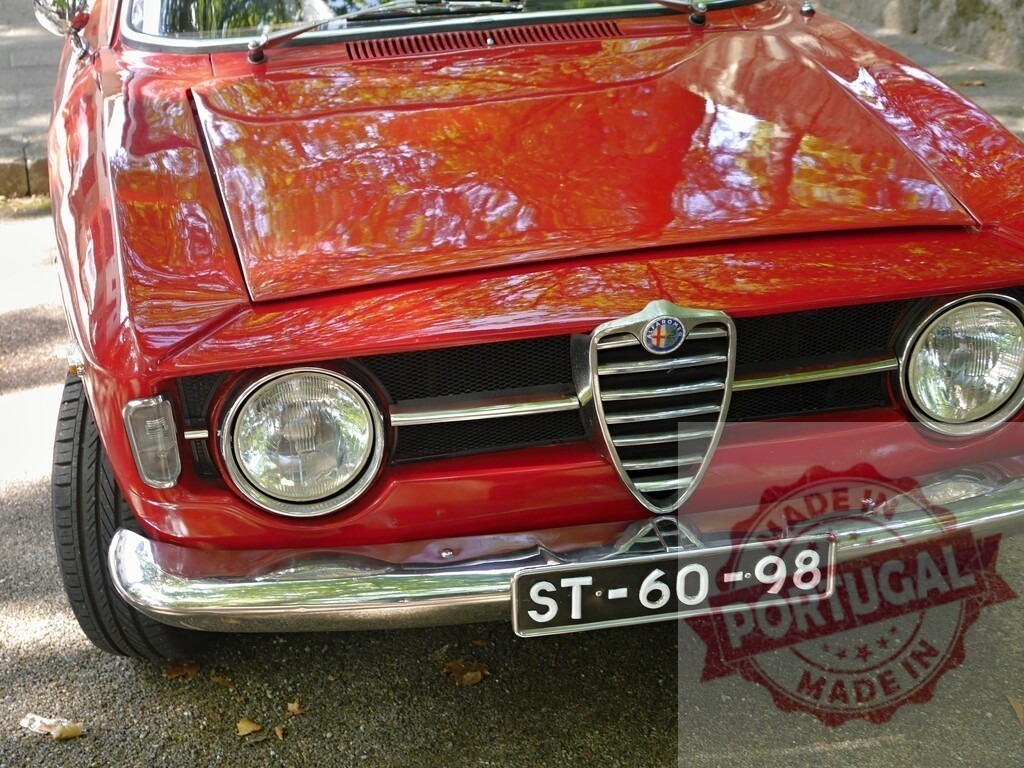 Red vintage Alfa Romeo car front detail | Red Alfa Romeo classic car showing front grille, headlights, and chrome bumper - Realisiert mit Pictrs.com