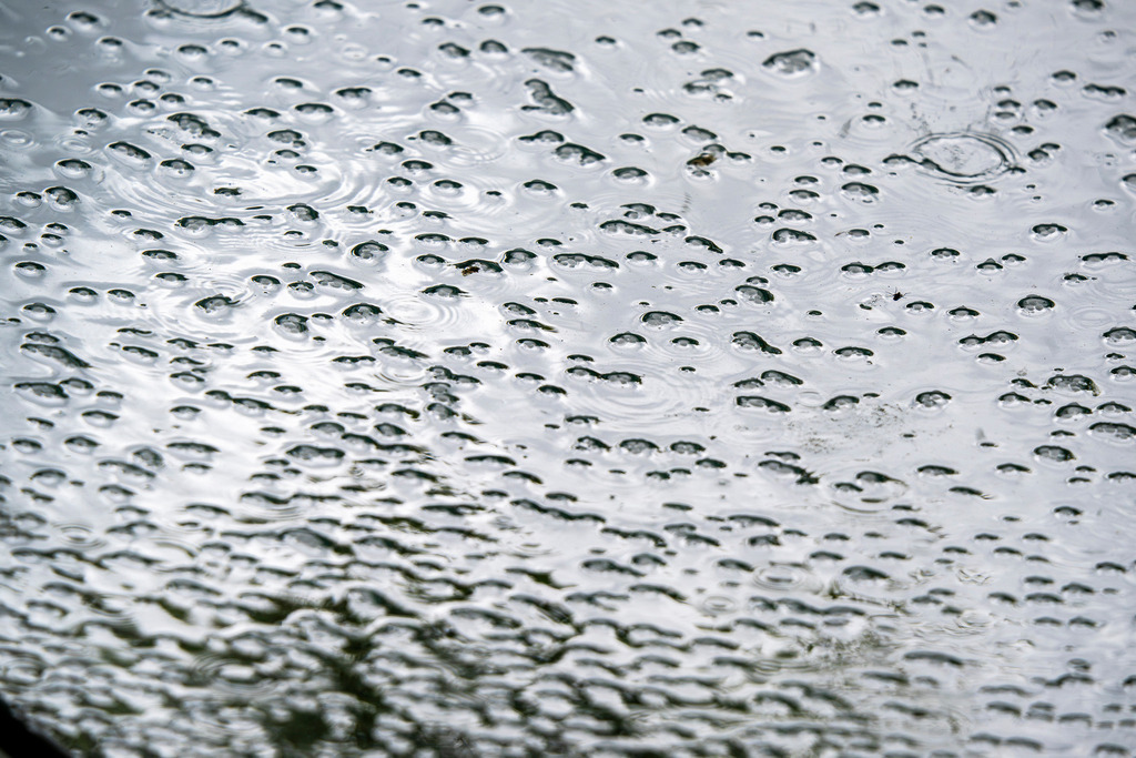 Regenballett auf glitzernder Fläche | Ein faszinierender Moment des Regens wurde hier eingefangen. Unzählige kleine Bläschen und Regentropfen tanzen auf einer hellen, metallisch glänzenden Oberfläche und erzeugen ein einzigartiges, rhythmische Muster. Die kühle Farbe des Untergrunds und die klare Form der Wassertropfen vermitteln eine beruhigende, meditative Stimmung. Es ist ein Bild, das die flüchtige Schönheit eines Regentages festhält und zum Innehalten und Träumen einlädt. Die perfekte Aufnahme für Naturliebhaber und Freunde minimalistischer Fotografie - Realisiert mit Pictrs.com