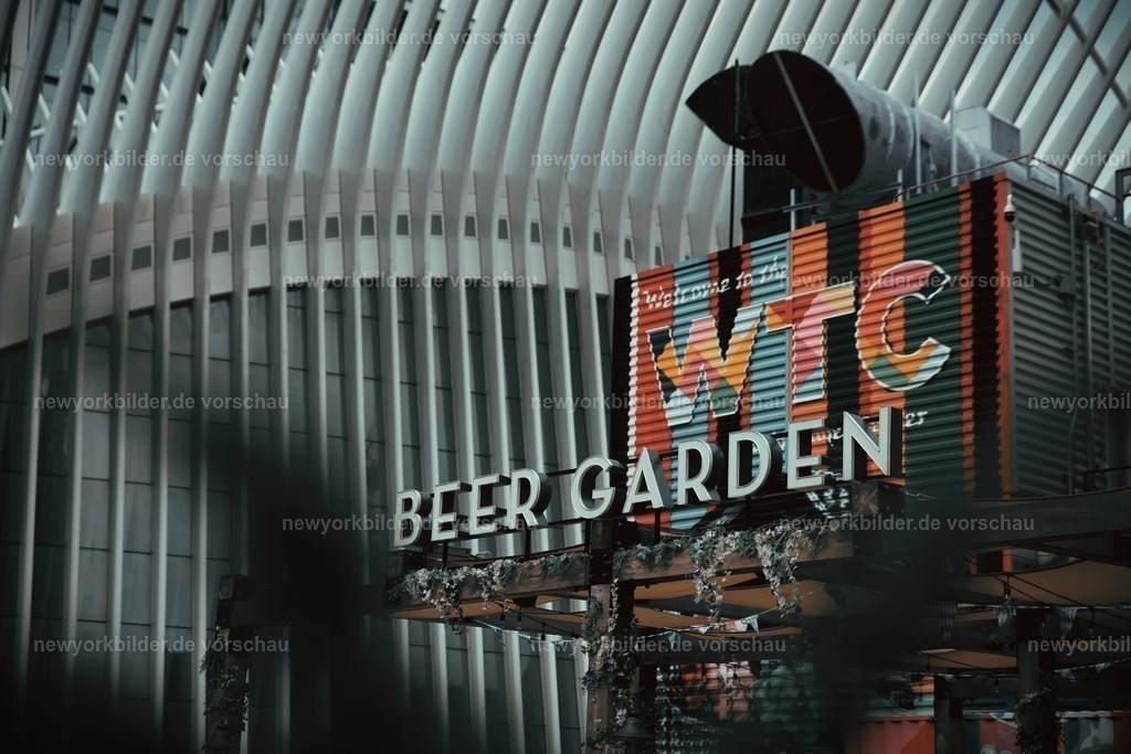 Sommer im Beer Garden draußen am Oculus | Mitten in Downtown Manhattan, direkt am futuristischen Oculus, liegt ein Ort, der pure Sommerstimmung versprüht: der beliebte Beer Garden. Hier treffen sich Touristen aus aller Welt, um eine Pause vom pulsierenden Stadtleben zu genießen. Die Sonne taucht die weißen Bögen des Oculus in strahlendes Licht, während im Hintergrund die imposanten Türme des World Trade Centers die Skyline prägen. Menschen sitzen entspannt an rustikalen Tischen, stoßen mit kühlen Getränken an und lassen den Blick über die beeindruckende Architektur schweifen. Es ist ein Ort, an dem die Hektik der Metropole für einen Moment verschwindet und die Leichtigkeit des Sommers spürbar wird. Gespräche, Lachen und das Klirren der Gläser verschmelzen mit dem urbanen Soundtrack der Stadt. Dieses Bild fängt die perfekte Balance zwischen moderner Architektur und menschlicher Begegnung ein – ein Stück New York, das Lebensfreude und Gemeinschaft verkörpert. Wer die Stadt liebt, findet hier einen magischen Platz, um Energie zu tanken und den Sommer in seiner schönsten Form zu erleben.