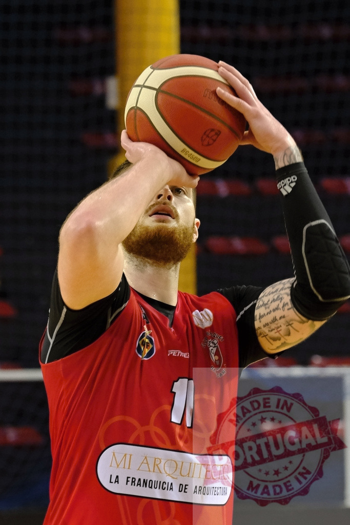 Basketball player concentrating on shooting free throw during game | Basketball player in a red jersey holding the ball, aiming for a shot - Realized with Pictrs.com