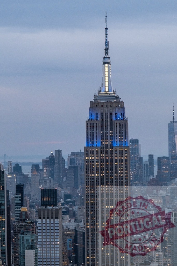 Empire State Building standing tall over New York City at dusk | Empire State Building illuminated in blue at dusk, showcasing its iconic architecture against the New York City skyline - Realized with Pictrs.com