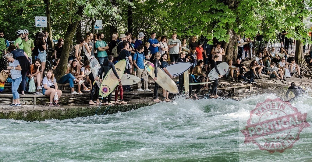 Surfers and spectators enjoying Eisbach wave in Munich | Surfers riding Eisbach wave in the Englischer Garten in Munich, Germany, while crowd of spectators watching - Realized with Pictrs.com