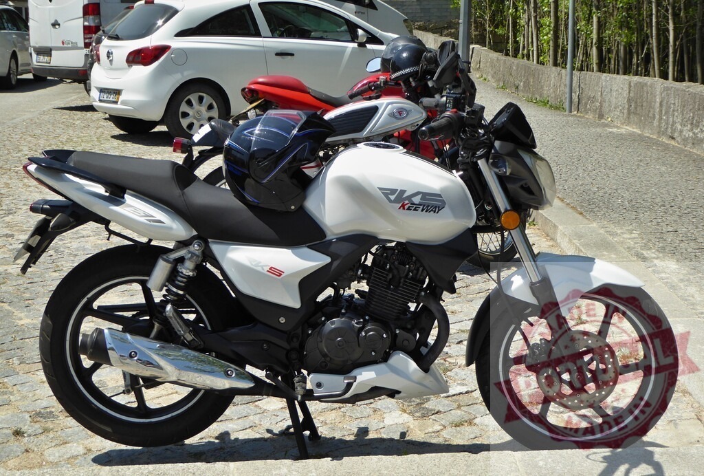 White Keeway RKS 125 motorcycle parked on cobblestone street | Modern white Keeway RKS 125 motorcycle parked on a cobblestone street - Realized with Pictrs.com