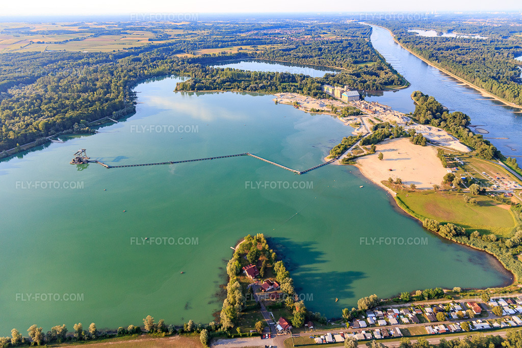 Aerial view: Gravière EPPLE, Le Salmengrund gravel pit with motorhome parking in Seltz in the state Bas-Rhin, France. – Photo: IMG_109165.jpg taken on 07/25/2018 by Werner Riehm/FLY-FOTO.com – Resolution of the original: 5472 x 3648 px – CAMPING-CAR PARK - Aires d'étape et de services pour Camping-Car