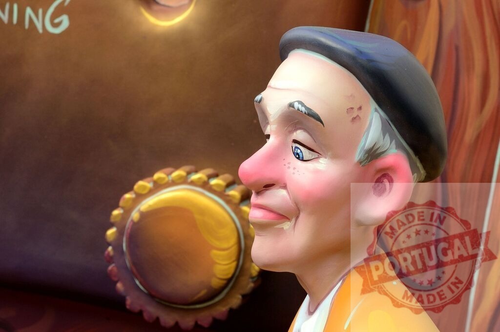 Smiling caricature man wearing beret at Fallas festival | Sculpted man's head with a painted, cartoon-like expression, part of a cheerful outdoor display - Realized with Pictrs.com
