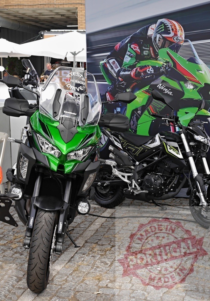 Kawasaki versys 1000 and z400 presented at motorcycle show | Kawasaki motorcycles presented at a motorcycle show with a Kawasaki racer in the background - Realisiert mit Pictrs.com