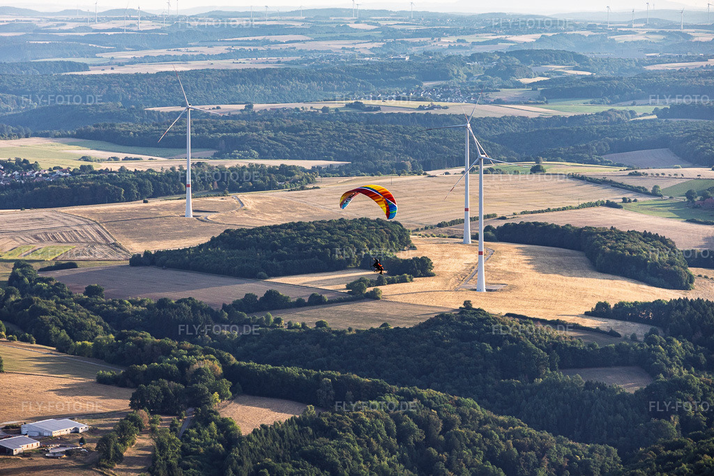 Luftbild: Gleitschirm vor dem Wndpark am Einöderwiesenhof in Riedelberg im Bundesland Rheinland-Pfalz in Deutschland. – Foto: IMG_158682.jpg vom 15.08.2026 durch Werner Riehm/FLY-FOTO.de – Auflösung des Originals: 5679 x 3786 px