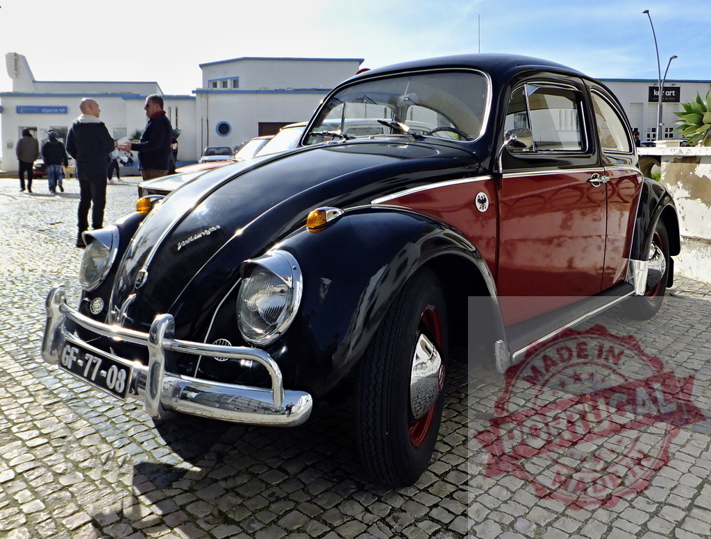 Classic Volkswagen Beetle parked on cobblestone street, attracting attention from car enthusiasts | Restored Volkswagen Beetle shining in the sun, parked on a cobblestone street near other people admiring vintage cars - Realized with Pictrs.com