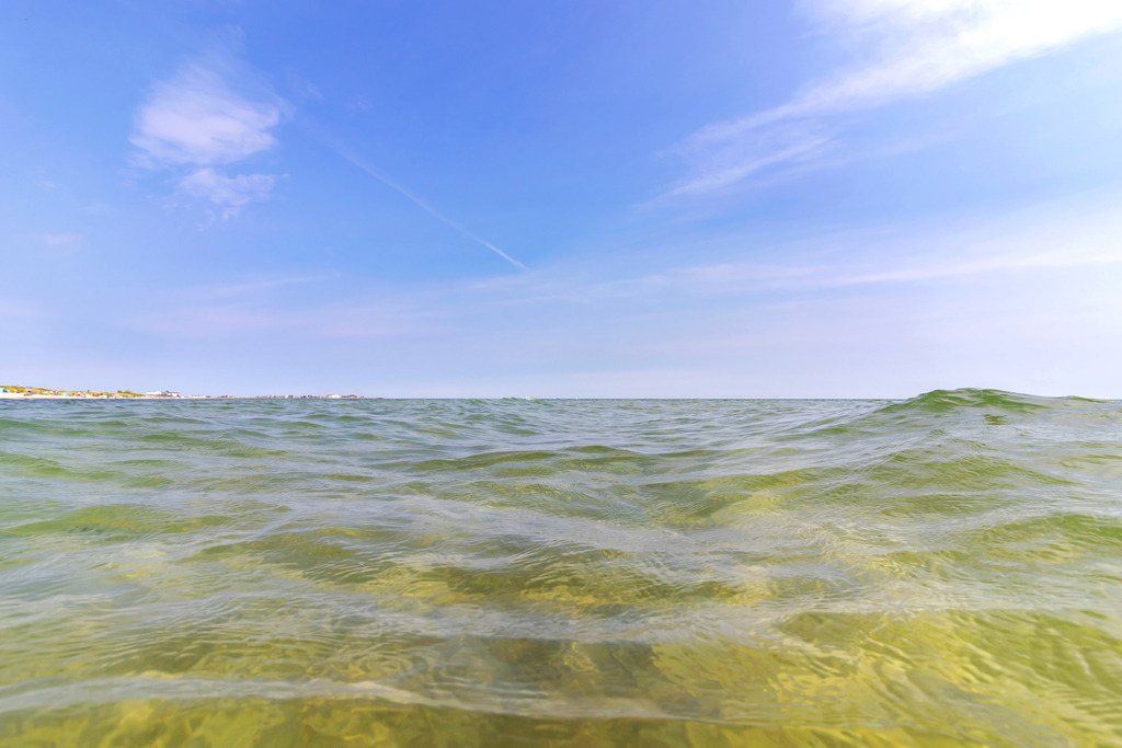 Wandbild: Badetag in Schönhagen | Dieses Wandbild im Querformat zeigt ein Foto welches in der Ostsee aufgenommen wurde. In der Ferne kann man den Sandstrand in Schönhagen erahnen. Am Himmel sind einige Schleierwolken zu sehen.  - Realisiert mit Pictrs.com