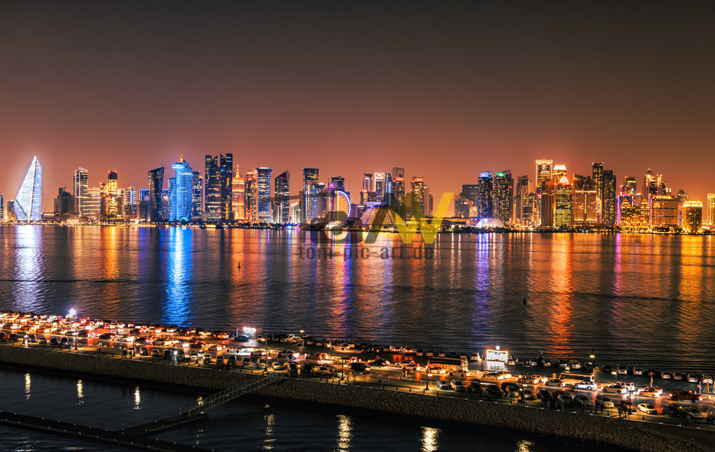 Strahlende Skyline von Doha------Lichterglanz auf dem Meer 2 | Das Bild zeigt die beleuchtete Skyline von Doha, Katar, bei Nacht, aufgenommen von der Doha Corniche. Die Doha Corniche ist eine sieben Kilometer lange Uferpromenade entlang der halbmondförmigen Bucht von Doha. Sie verbindet das moderne Geschäftsviertel Al Dafna im Norden mit den historischen Teilen der Altstadt Dohas im Süden. Die Gegend ist bekannt für ihre zahlreichen Wolkenkratzer, Luxushotels, Parks und das Museum für Islamische Kunst.  - Realisiert mit Pictrs.com