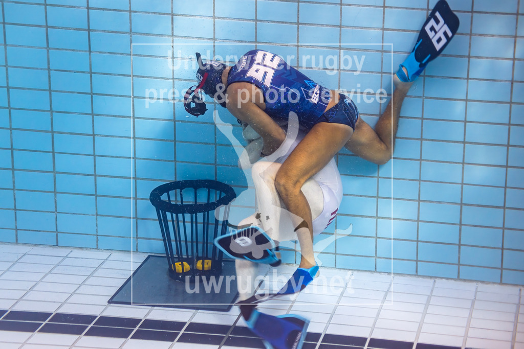 24. - 26.11.2023: Unterwasser-Rugby Champions Cup 2023  | Ecomares (Kolumbien) in blau gegen Flipper (Dänemark) in weiß. Strafwurfwerfen - Pablo Alzate (blau #92) als Angreifer den dänischen Torwart Søren Nielsen (weiß #9), die Tauchmaske des Kolumbianers ist bei dem Angriff verloren gegangen und schwebt neben seinem Kopf. - Realisiert mit Pictrs.com