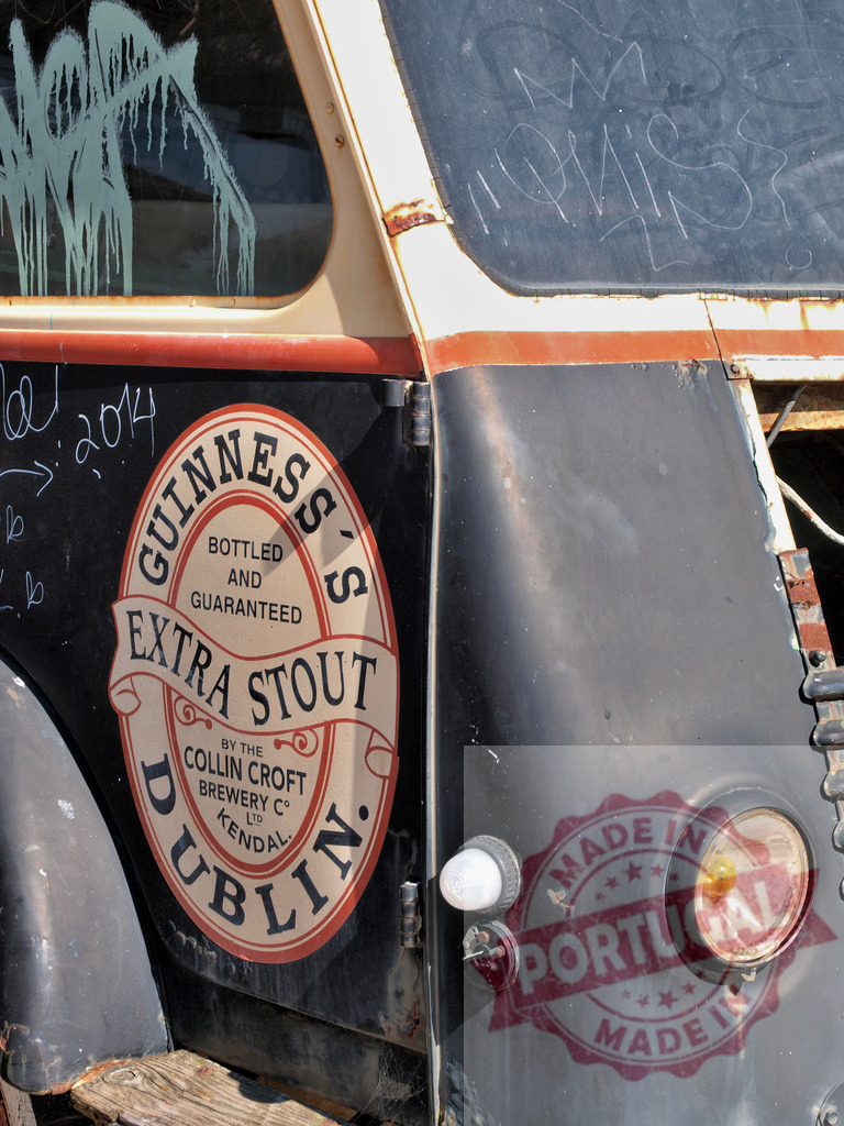Guinness Extra Stout logo on vintage weathered truck | Vintage truck featuring a weathered Guinness Extra Stout logo with urban graffiti - Realized with Pictrs.com