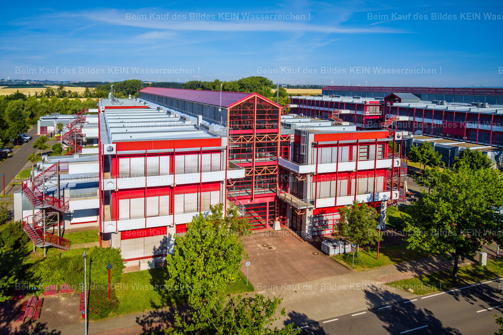 IGZ Barleben-0064 | Blick aus der tief fliegenden Drohne auf das markante rote Stahlgebäude des Innovations- und Gründerzentrums (IGZ) in Barleben. Die nahe Perspektive stellt die Architektur und die klare Konstruktion des Gebäudes in den Mittelpunkt.Die ungewöhnliche Farbgebung und die sichtbare Stahlstruktur verleihen dem Gebäude einen hohen Wiedererkennungswert. Durch die niedrige Drohnenperspektive entsteht ein deutlich anderer Eindruck als bei einer klassischen Standortaufnahme aus größerer Höhe.Das Motiv zeigt, wie sich auch einzelne Unternehmens- und Gewerbegebäude mit einer gezielt gewählten Perspektive prägnant darstellen lassen – nicht nur als Teil eines gesamten Gewerbestandortes, sondern als eigenständiges architektonisches Motiv. - Realisiert mit Pictrs.com