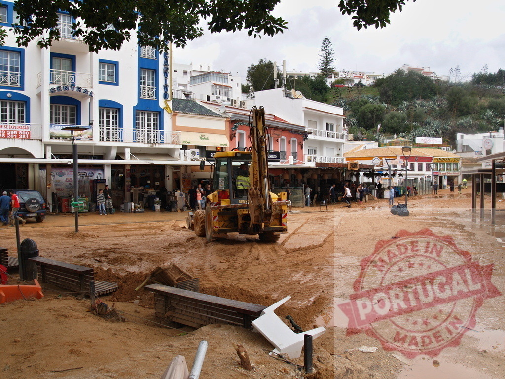 Bulldozer clearing mud after flood disaster in town | Albufeira Flood - discruction by weather problems Bulldozer clearing thick mud and debris from a street in a town after a flood - Realisiert mit Pictrs.com