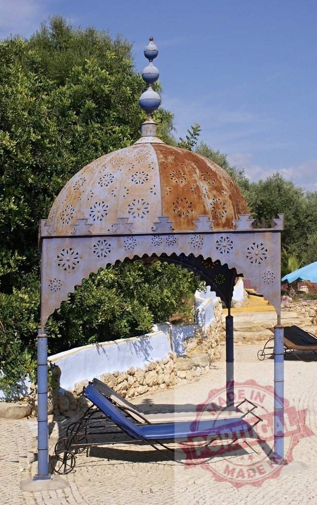 Ornate weathered blue gazebo with lounge chair in garden | Weathered blue ornate gazebo providing shade for a lounge chair in a sunny garden - Realized with Pictrs.com