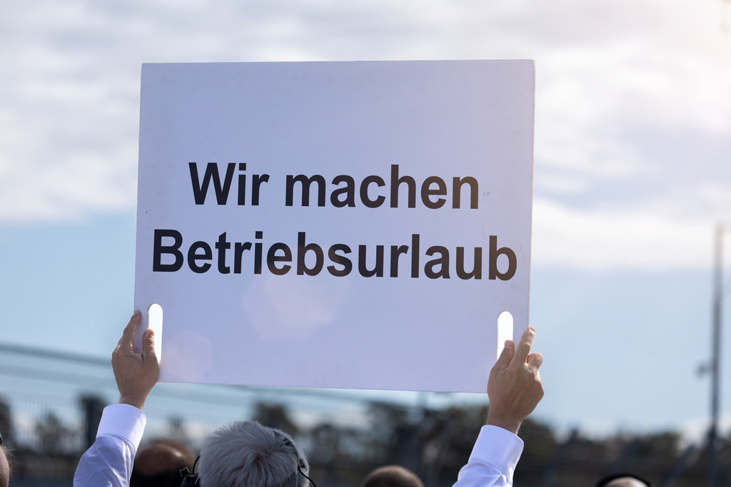 WIR MACHEN BETRIEBSURLAUB | Ein Schild mit dem Text WIR MACHEN BETRIEBSURLAUB wird in die Höhe gehalten - Realisiert mit Pictrs.com