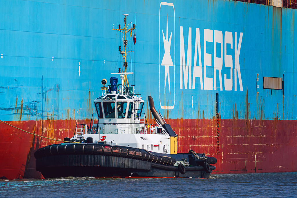 Kraftpaket am Giganten: PETER & Mærsk | Der Schlepper PETER im Einsatz vor der Bordwand der Mærsk Mc-Kinney Møller. Die Aufnahme zeigt das erste Schiff der Triple-E-Klasse beim Manövrieren im Hamburger Hafen. Im direkten Vergleich werden die enormen Größenverhältnisse der modernen Containerlogistik und die Präzisionsarbeit der Assistenzschlepper deutlich. - Realisiert mit Pictrs.com