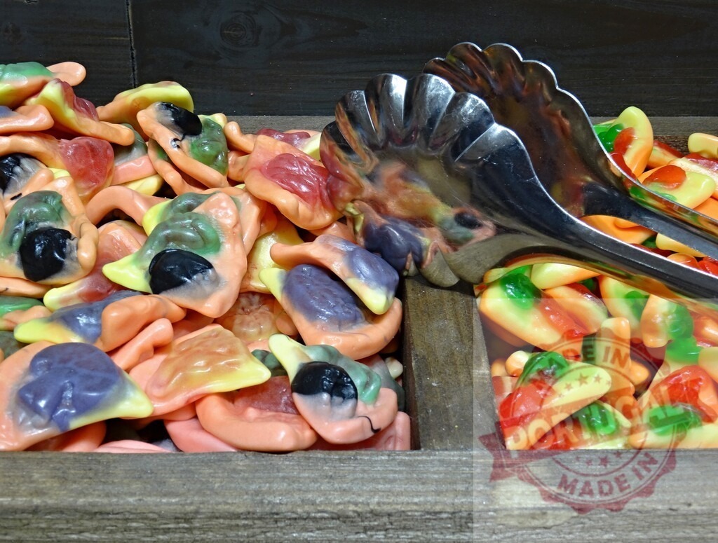Colorful gummy candy bulk bin with tongs for picking | Colorful gummy candies with various shapes and flavors in a wooden bulk bin - Realized with Pictrs.com