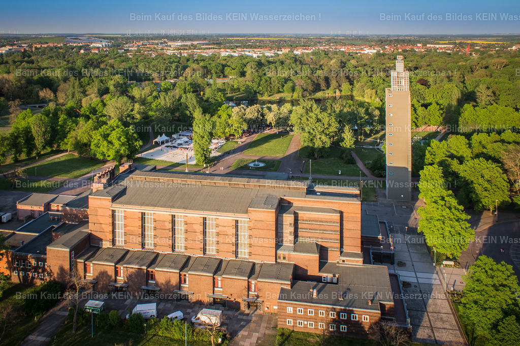 1_Magdeburg Moderne Lehmann_Stadthalle_-6891 | Die Stadthalle und der Albinmüller-Turm im Stadtpark Rotehorn zählen zu den bedeutendsten Architekturensembles der Magdeburger Moderne. Beide Bauwerke entstanden anlässlich der Deutschen Theaterausstellung 1927 nach den Entwürfen des Architekten Albinmüller und stehen bis heute für den kulturellen und architektonischen Aufbruch der Weimarer Republik. Mit ihrer klaren Formensprache, den expressionistischen Elementen und ihrer großzügigen Einbindung in den Stadtpark gehören sie zu den bekanntesten Wahrzeichen Magdeburgs. Die Stadthalle war von Beginn an als repräsentativer Veranstaltungsort für Konzerte, Kongresse und kulturelle Großereignisse konzipiert. Der 60 Meter hohe Albinmüller-Turm diente als Aussichtsturm und bot schon damals einen beeindruckenden Blick über den Stadtpark, die Elbe und die Magdeburger Altstadt. Gemeinsam mit dem Pferdetor entstand ein einzigartiges Gesamtkunstwerk aus Architektur, Landschaft und Kultur, das den hohen gestalterischen Anspruch der 1920er-Jahre eindrucksvoll widerspiegelt. Heute prägen Stadthalle und Albinmüller-Turm das Gesicht des Stadtparks Rotehorn wie kaum ein anderes Bauwerk. Nach der umfassenden Sanierung der Stadthalle knüpft das Ensemble wieder an seine ursprüngliche Bedeutung als Kultur- und Veranstaltungszentrum an und erinnert zugleich an eine Epoche, in der Magdeburg mit visionärer Architektur und innovativem Städtebau deutschlandweit Maßstäbe setzte. - Realisiert mit Pictrs.com