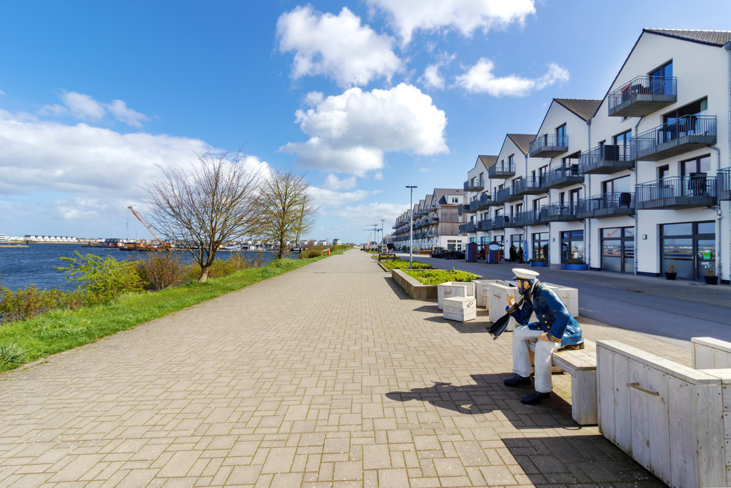 Wandbild: Promenade in Olpenitz | Dieses Wandbild im Querformat zeigt die Promenade in Olpenitz im Frühling. Der blaue Himmel zeigt einige schöne Wolken. - Realisiert mit Pictrs.com