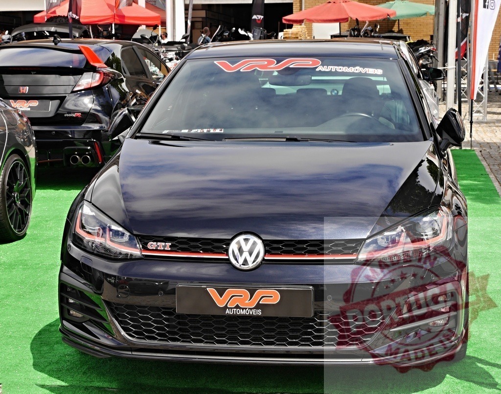 Black Volkswagen Golf GTI at car show | Volkswagen Golf GTI displayed at an outdoor car event on green carpet - Realisiert mit Pictrs.com