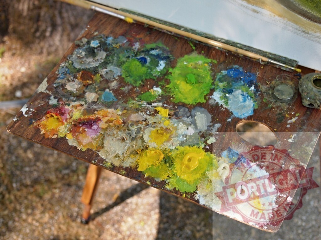 Artist palette with oil paints creating abstract texture | Wooden artist palette with colorful oil paints and brushes resting on an easel outdoors - Realisiert mit Pictrs.com