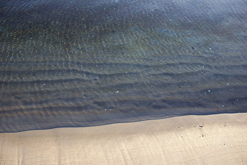 Wandbild: Ruhiges Wasser am Strand in Damp | Dieses Wandbild im Querformat zeigt den Strand und das Meer in Nahaufnahme. Auf der Ostsee befinden sich nur sehr kleine Wellen. Im Vordergrund befindet sich der helle Strand.  - Realisiert mit Pictrs.com