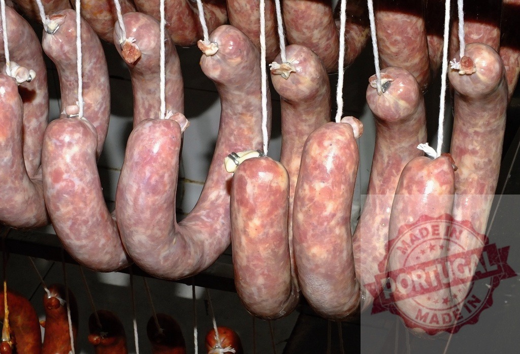 Artisan sausages hanging, curing in a charcuterie environment | Freshly made artisan sausages hanging for curing and drying in a dark room - Realisiert mit Pictrs.com