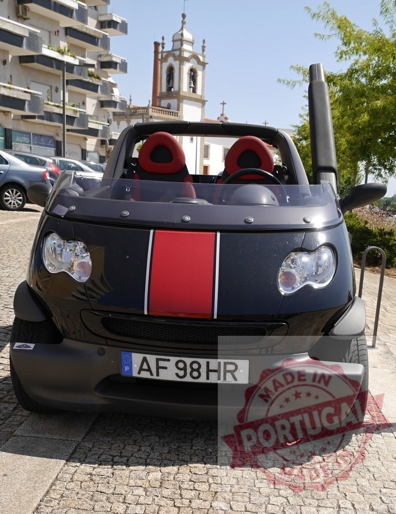 Smart Crossblade parked on a historic Portugal street | Smart Crossblade parked on cobblestone pavement with a church tower in the background - Realisiert mit Pictrs.com