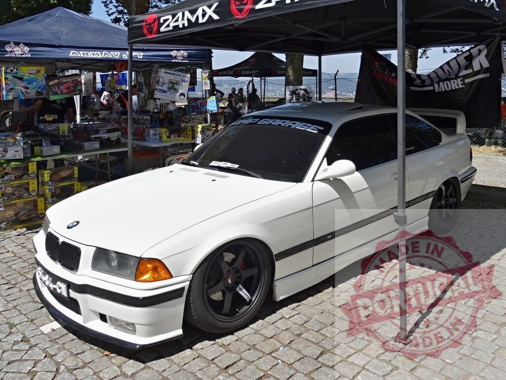BMW E36 coupe with custom modifications at car festival | White modified BMW E36 coupe showcasing tuning and style at an outdoor car show - Realized with Pictrs.com