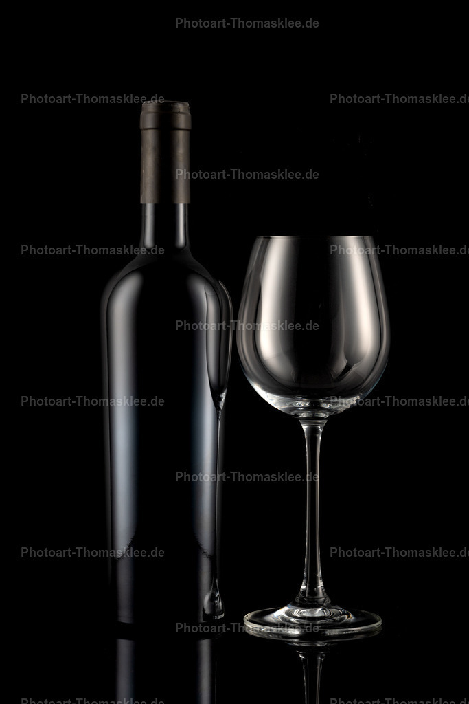 Rotwein Stillleben - Flasche und Glas auf dunklem Grund | Eine klassische Weinkomposition präsentiert sich in diesem atmosphärischen Schwarz-Weiß-Stillleben. Die Weinflasche und das bauchige Glas bilden eine harmonische Einheit vor dem tiefen schwarzen Hintergrund. Subtile Lichtreflexe auf den glatten Oberflächen schaffen Tiefe und Eleganz. Die schlichte Anordnung konzentriert den Blick auf die pure Schönheit der Glasformen. Dieses zeitlose Motiv eignet sich hervorragend für edle Weinpräsentationen oder anspruchsvolle Wanddekoration. - Realisiert mit Pictrs.com