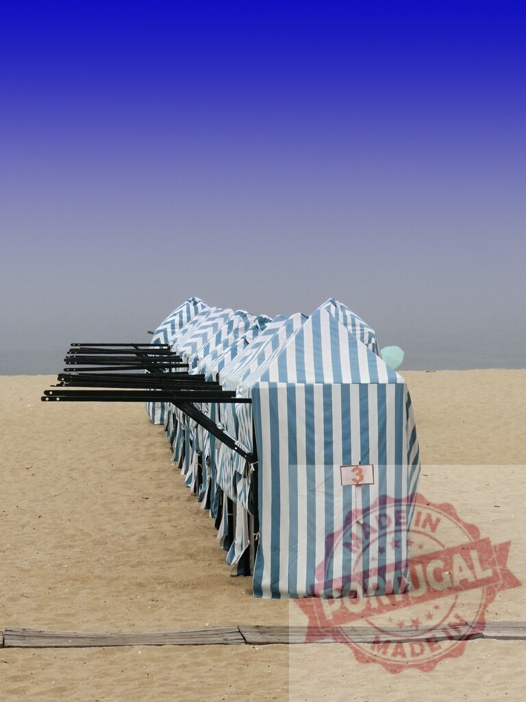 Beach cabins lining sandy ocean beach under blue sky. Aveiro - Portugal | Striped beach changing cabins extending along a sandy shore with ocean and blue sky - Realisiert mit Pictrs.com