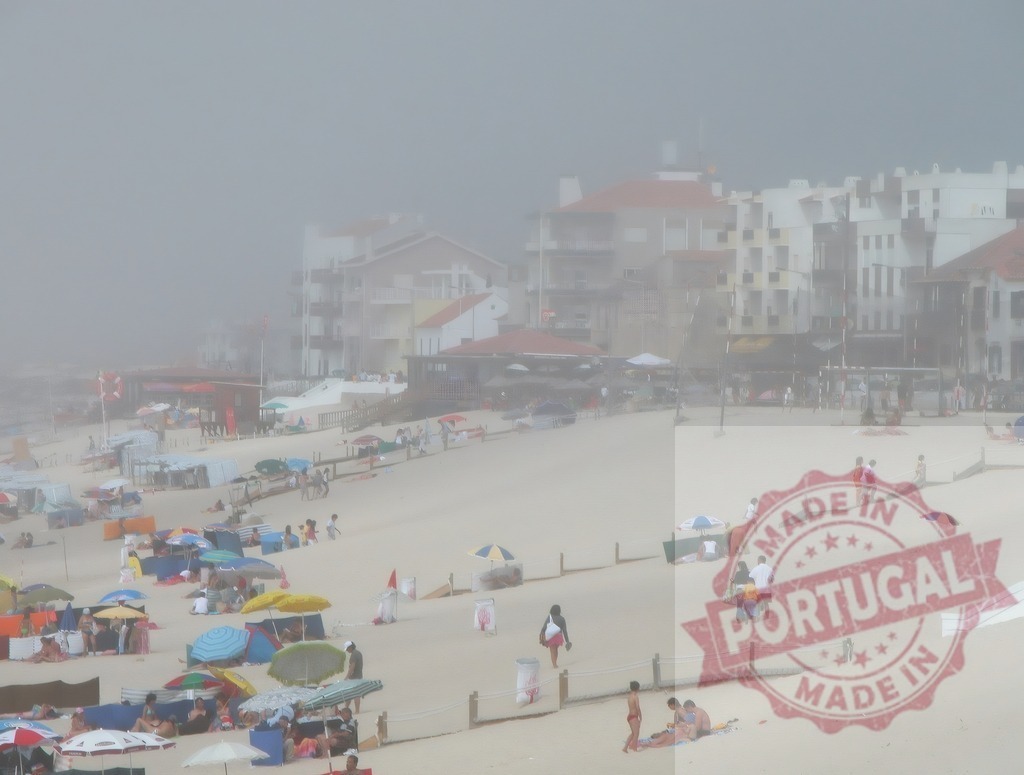 Beachgoers relaxing beneath umbrellas on a foggy day. Centro Portugal | People enjoying a beach vacation with umbrellas and buildings obscured by dense fog - Realized with Pictrs.com