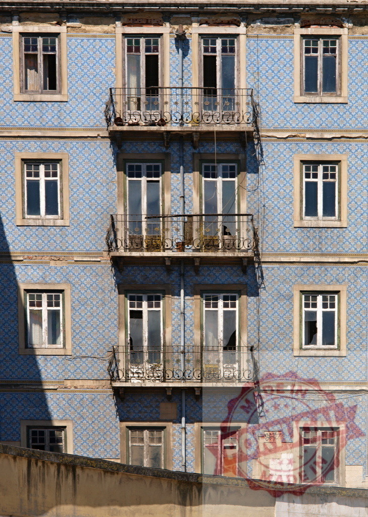 Lisbon tiled facade featuring azulejo architecture and balconies | Portuguese building facade covered in blue patterned azulejo tiles with balconies and windows - Realized with Pictrs.com