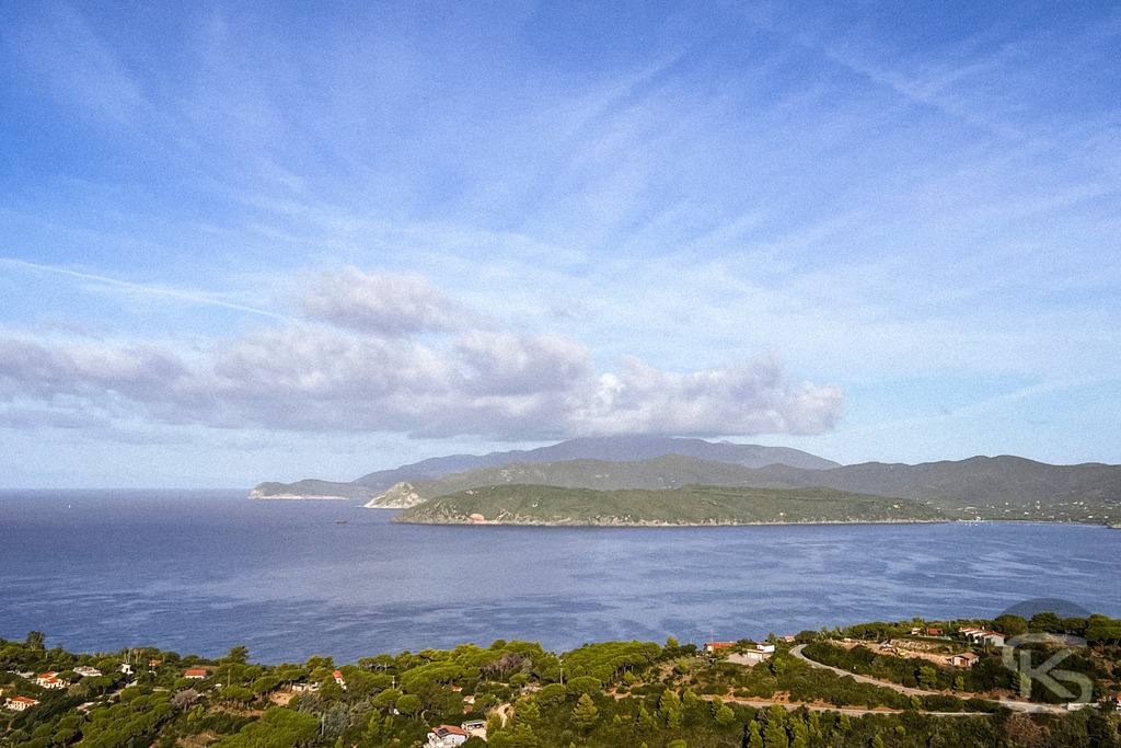 Morgenerwachen bei Capoliveri: Panorama-Blick auf Elba – Wandbild | Weitwinkel-Ansicht bei Capoliveri auf Elba bei Sonnenaufgang; vorne im Bild die terrassenförmig angelegten Häuser des Dorfes, links der Blick über die bewaldete Küste und das blaue Meer bis zum Horizont. - Realisiert mit Pictrs.com
