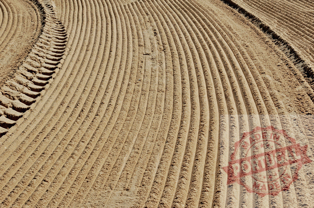 Tire tracks disturbing perfect lines on groomed sand surface | Tire tracks are disturbing perfect lines on a groomed sand surface, creating a contrast between order and disruption - Realisiert mit Pictrs.com